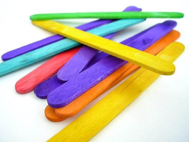 Colorful wooden craft sticks scattered on a white background.