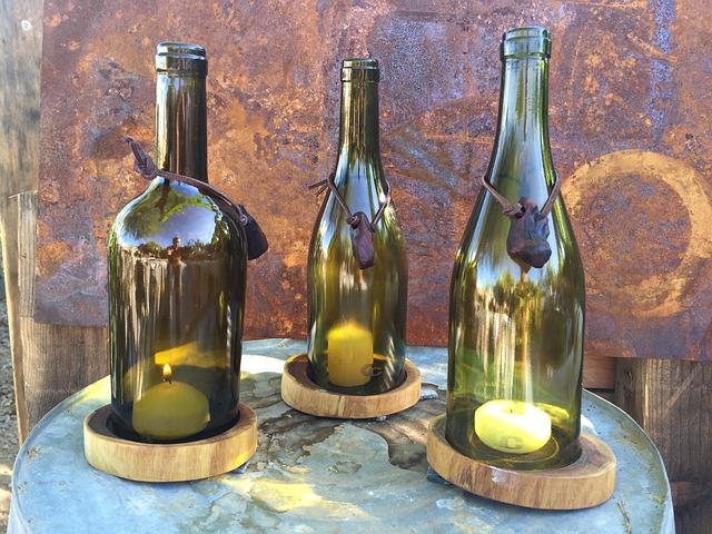 Three glass bottles with candles inside sit on wooden bases, creating a rustic display.