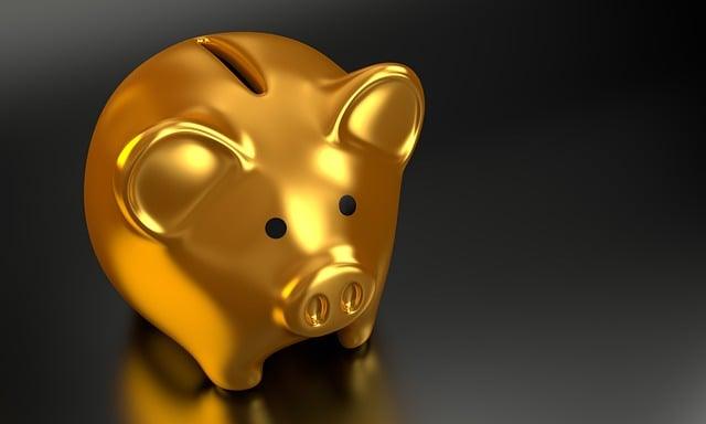 Golden piggy bank on a reflective black surface.